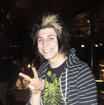 Jaime Preciado from American rock band Pierce The Veil holding up a "peace" sign with his hand while smiling.